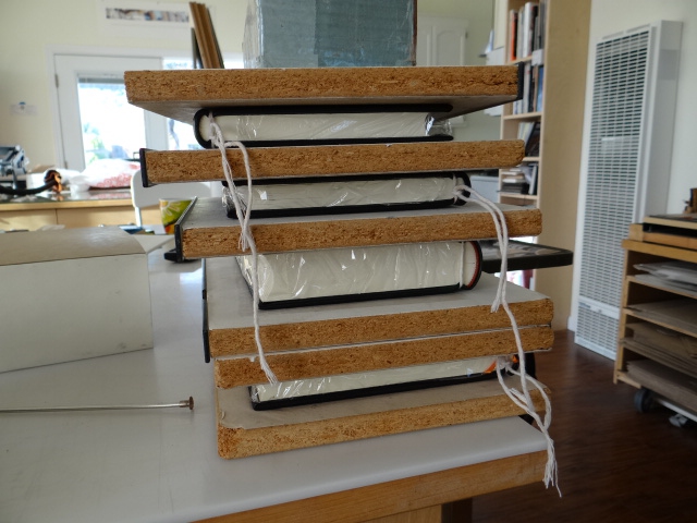 Four books freshly covered in goat skin and drying under weight