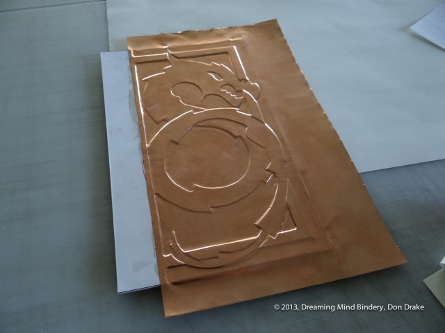 Debossing the copper onto the three dimensional substrate to create a copper journal cover