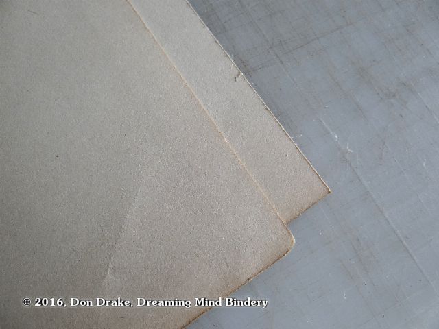 A detail showing two old sheets of paper; one with edges worn with time and use, the other showing freshly cut edges