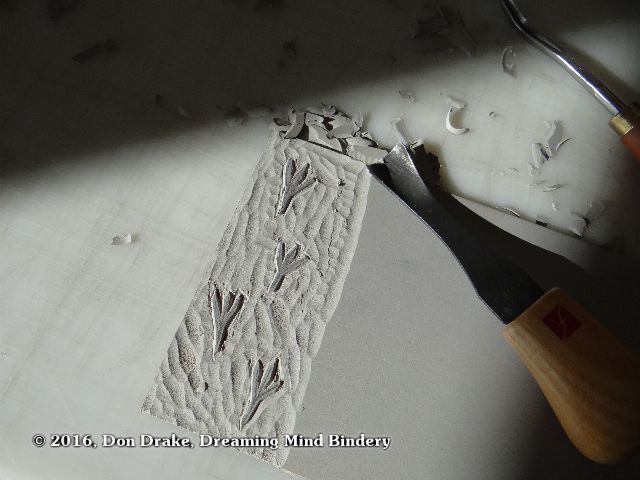 A linoleum block carved to print a pattern of chicken tracks 