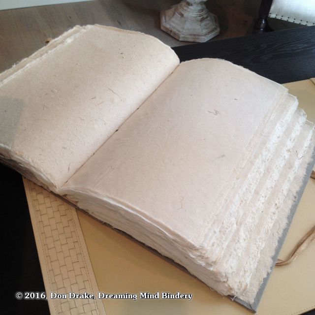 A large, hand bound blank book filled with handmade paper